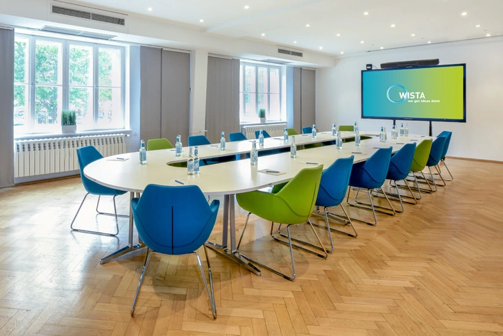 Pasteur-Kabinett mit großem Konferenztisch in der Mitte, bunten Sesseln und großen Fenstern